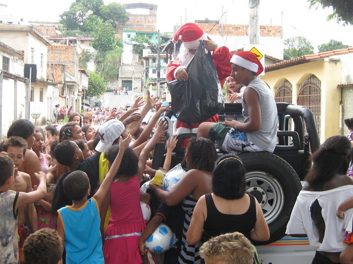 Santa handing out candy and plastic balls from a pickup truck surrounded by children