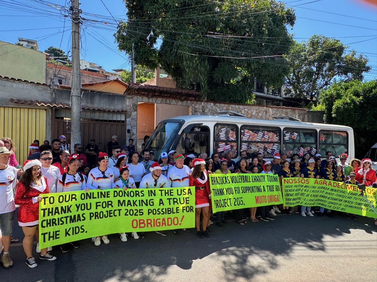 Volunteers and children in Belo Horizonte holding bright green banners thanking A True Christmas Project's online donors in the USA, Christmas 2025